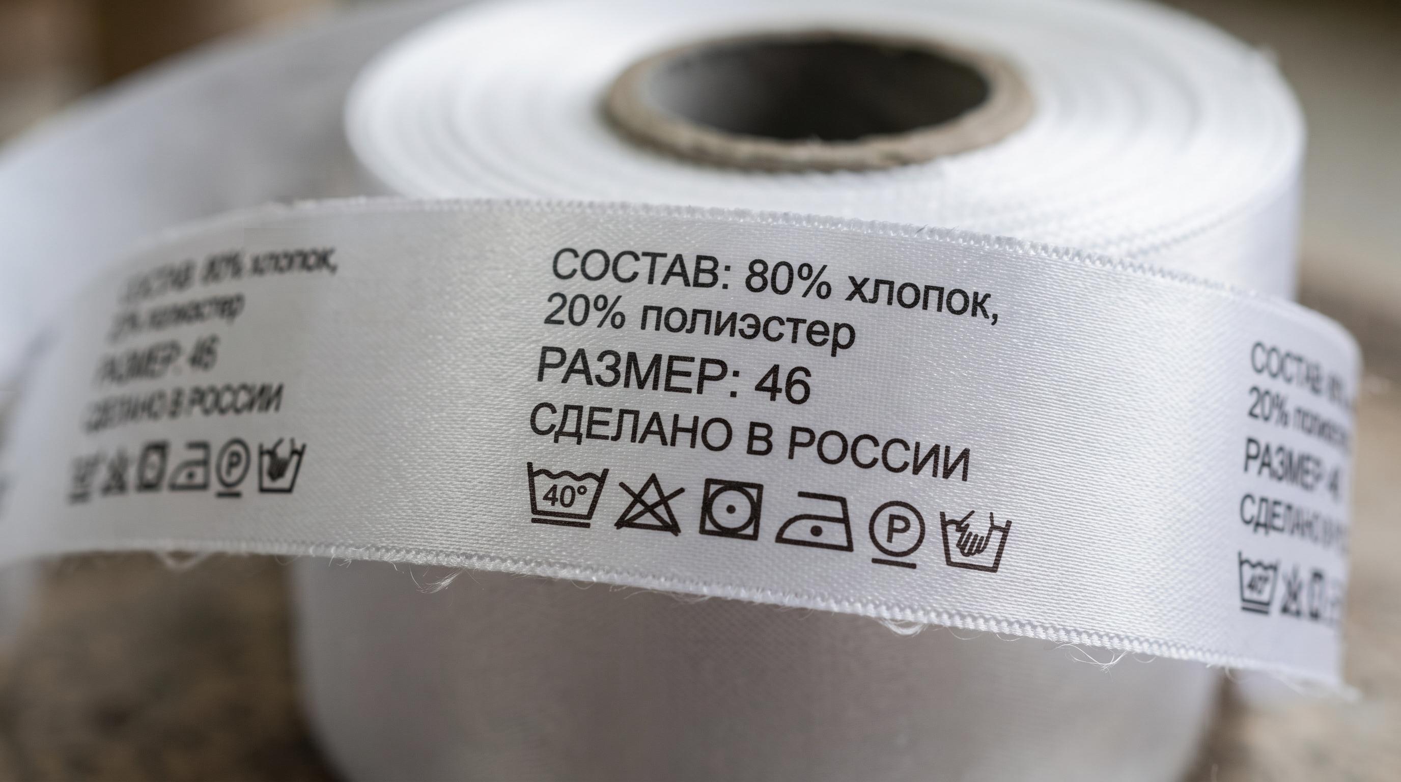 Рулон готовых тканевых нейлоновых этикеток высокой печати с русским текстом состава и символами ухода, крупный план